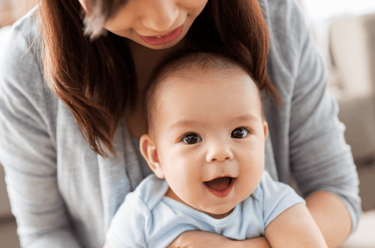 Mom holding her baby who is smiling at the camera