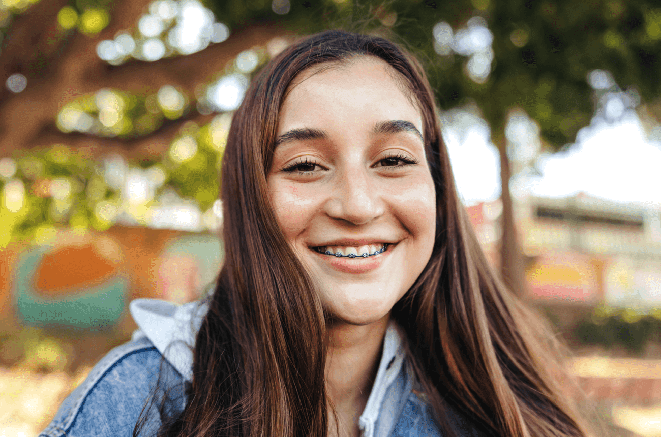 Teen girl standing outside and smiling at the camera