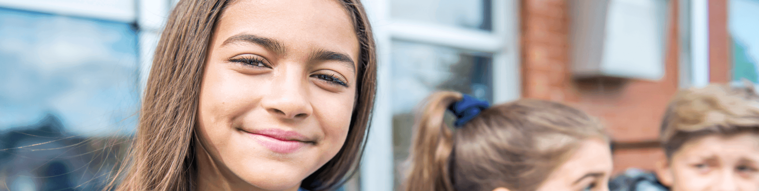 Girl standing outside and softly smiling at the camera