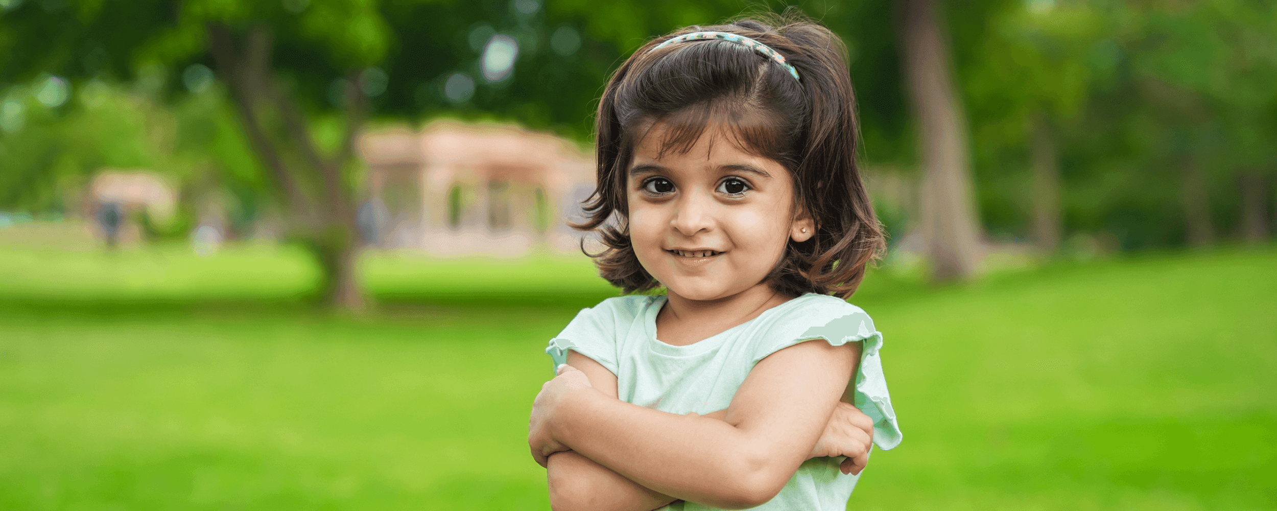 Young girl standing outside with her arms crossed smiling at the camera